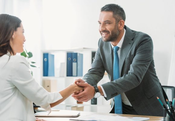 handsome-advisor-in-suit-shaking-hands-with-investor-at-workplace.jpg